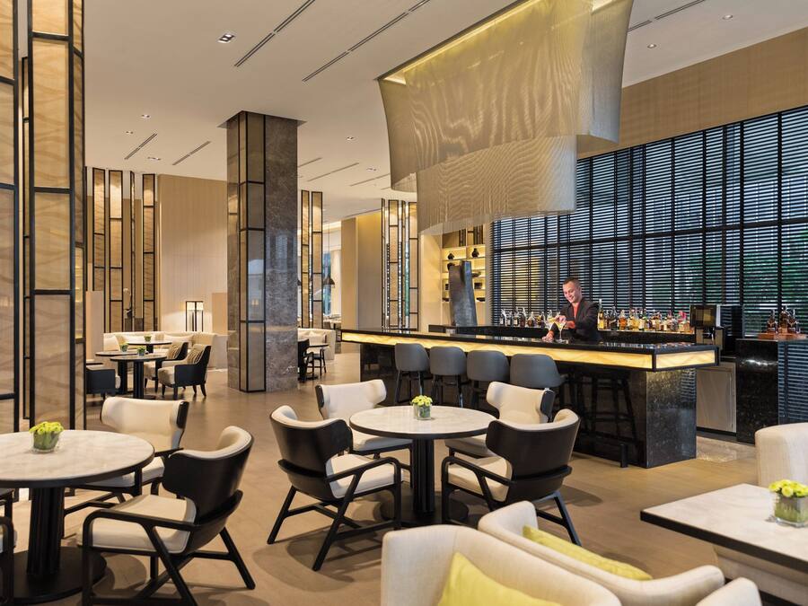 A modern bar area with a bartender, round tables, and bar stools.