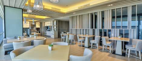 A modern restaurant with multiple seating areas, including tables and chairs, and pendant lighting.