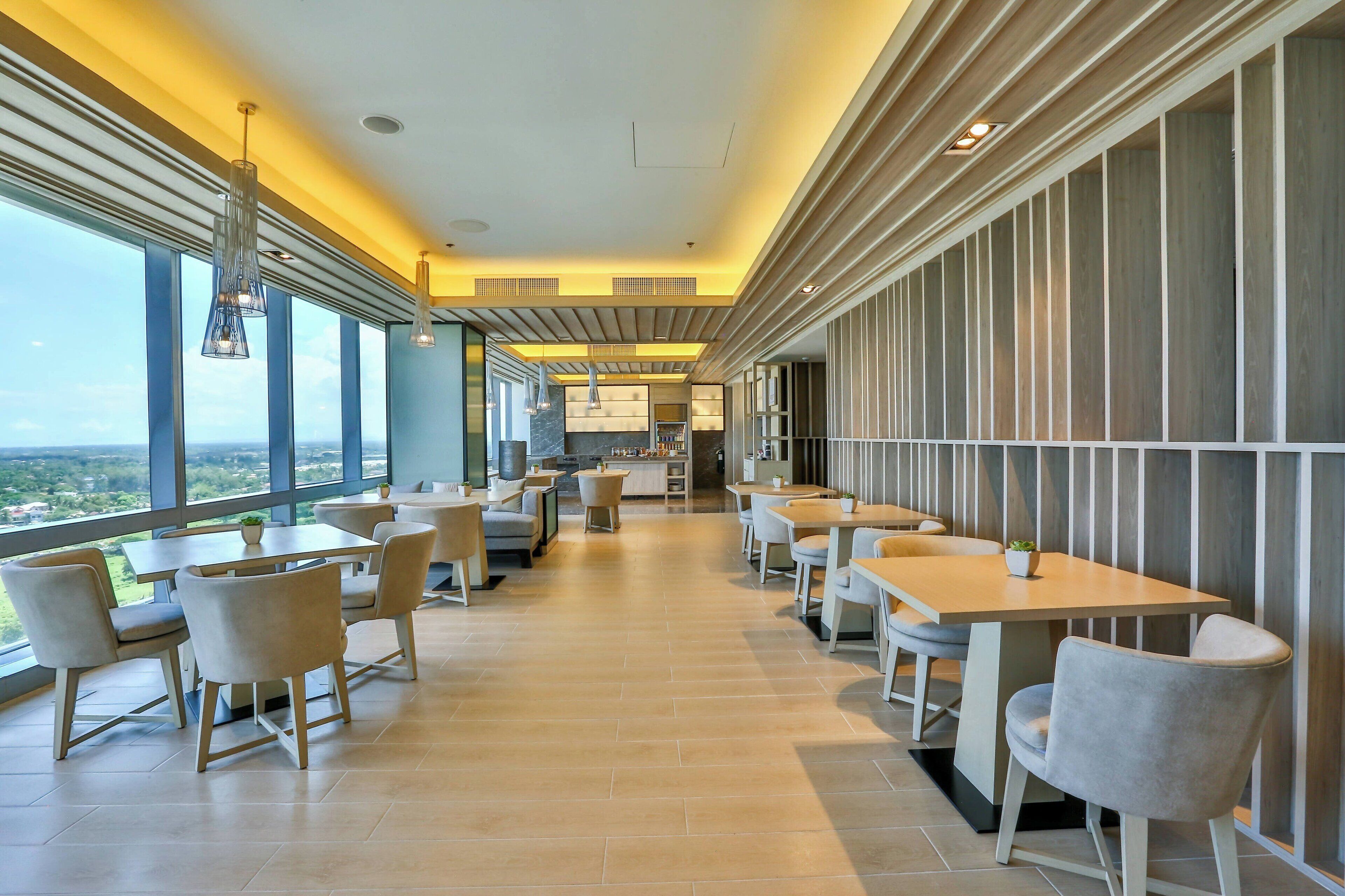 A modern dining area with large windows, contemporary furniture, and a view of the cityscape.