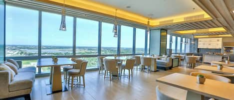 Un comedor moderno con ventanas amplias, techo alto y vistas a la ciudad.