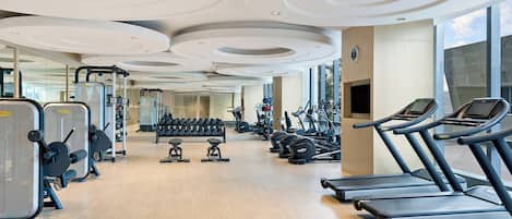 A gym with treadmills, weight machines, and dumbbells.