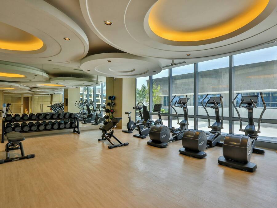 Een moderne sportschool met trainingsapparatuur, grote ramen en een houten vloer.