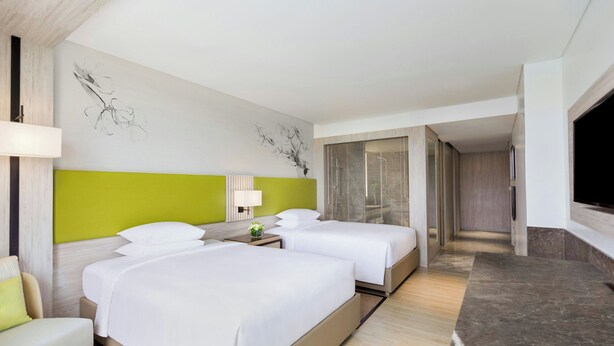 A hotel room with two beds, a TV, a desk, and a bathroom.
