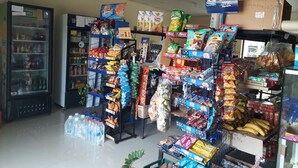 Una tienda de comestibles con estantes llenos de botanas, bebidas y otros productos.