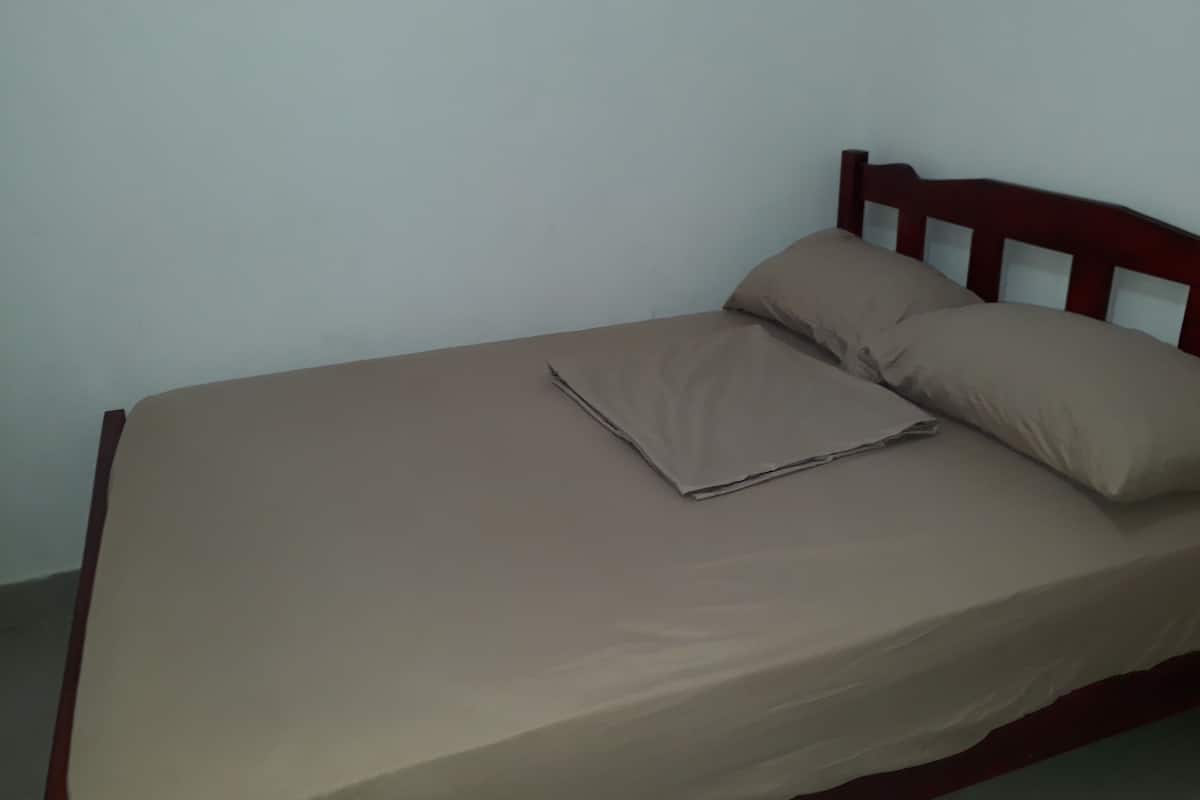 A single bed with a wooden headboard and a beige bedspread.