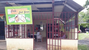 Un puesto de comida pequeño con un letrero verde que anuncia 'Fonda Lisseth Yariela' y número de contacto.