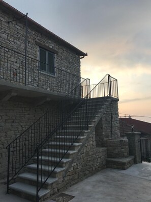 A stone building with a staircase leading to a balcony.