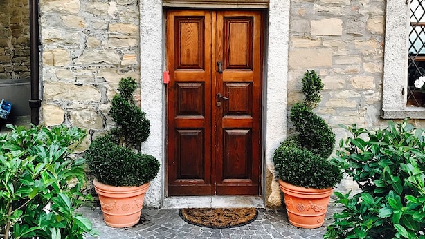 A stone building with a wooden double door, potted plants, and a sign reading "OSTERIA DEL BRAMANTE". - Albergo del Bramante (Roccaverano)