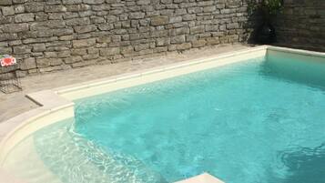 Een buitenzwembad, parasols bij het zwembad en ligstoelen