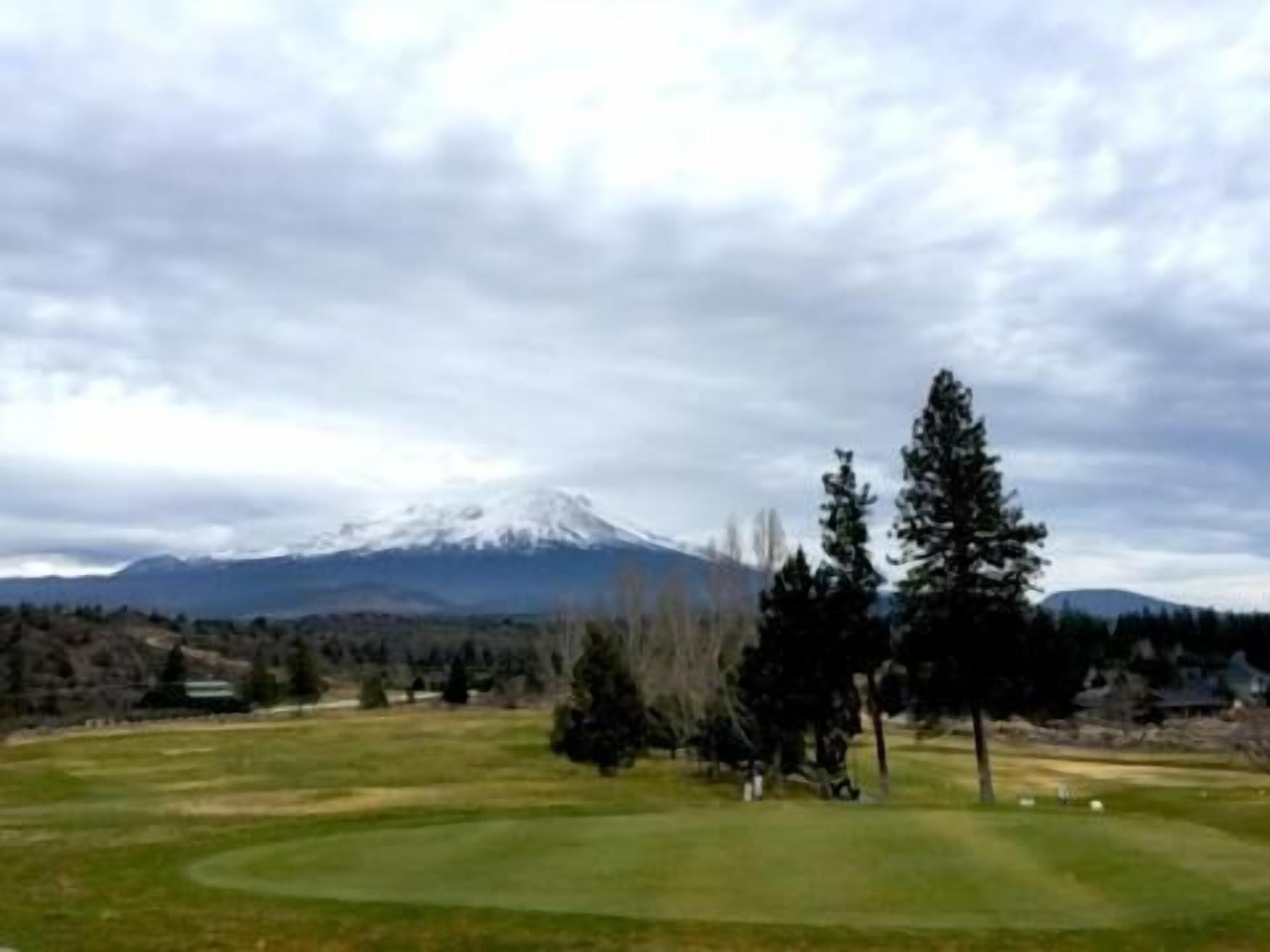 Un campo de golf con una montaña al fondo.