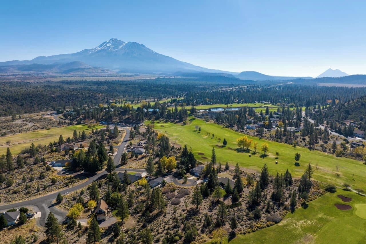 Un quartier résidentiel avec des maisons, un terrain de golf et une montagne en arrière-plan.