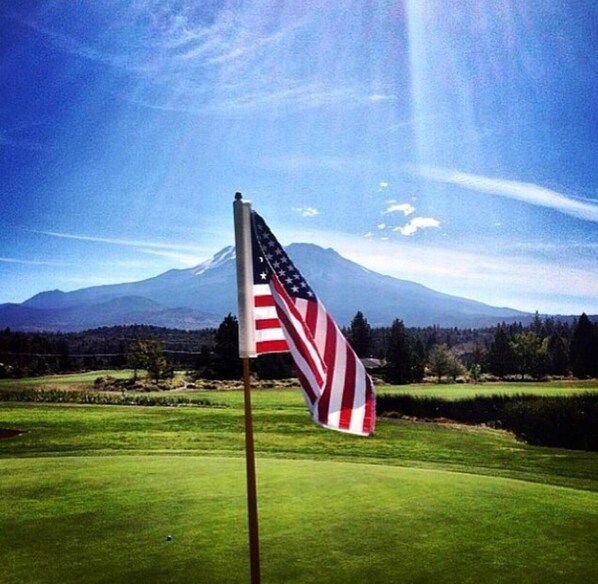 A flagpole with an American flag in front of a mountain landscape. - Lake Shastina Golf Resort (Weed)