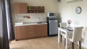 Eine kompakte Küche mit Holzausstattung, einer Mikrowelle, einem Kühlschrank und einem Essbereich mit Tisch und Stühlen.