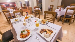 A restaurant with multiple tables set for dining, featuring plates of food, glasses, and cutlery. - Hotel Paraiso Trujillo (Trujillo)