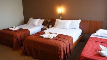 A hotel room with two single beds, a wooden headboard, a nightstand with a phone, and a wall-mounted light.