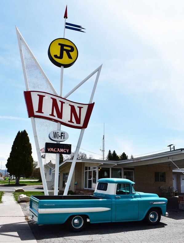 A vintage turquoise Chevrolet truck parked in front of a motel named 'INN' with a 'R' sign, Wi-Fi availability, and a 'SORRY NO VACANCY' sign.