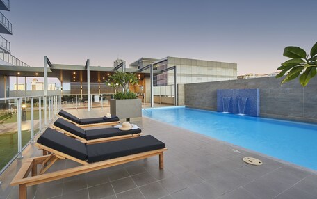 An outdoor swimming pool with lounge chairs and a glass railing.