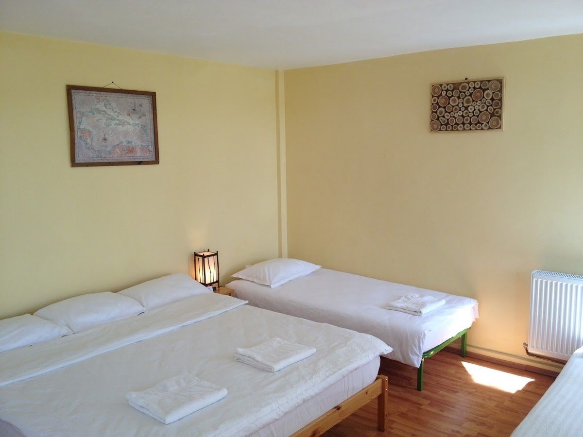 Una habitación con dos camas individuales, un mapa colgado en la pared, un panel de madera decorativo y un radiador.
