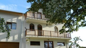 A two-story building with a balcony, a garage, and potted plants. - Belegania (Oarja)