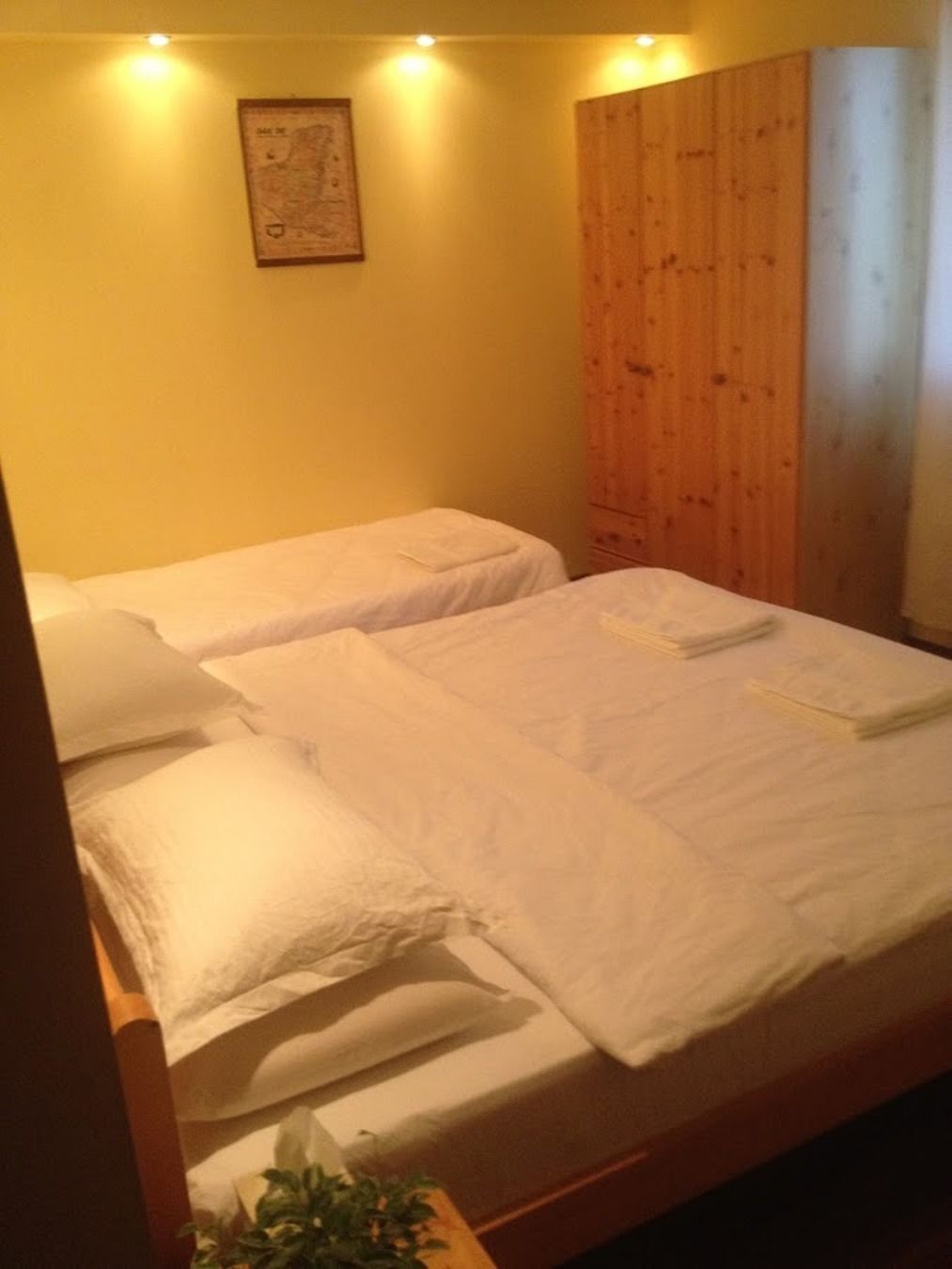 A room with two single beds, a wooden wardrobe, and a map on the wall.