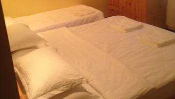 A room with two single beds, a wooden wardrobe, and a map on the wall.