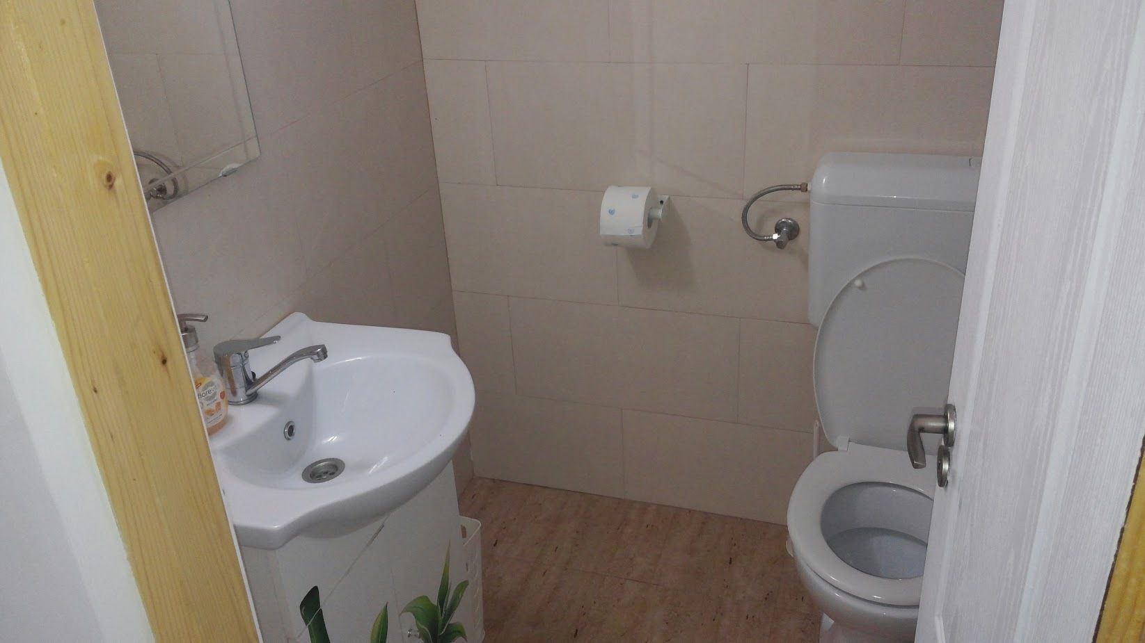 A small bathroom with a sink, toilet, and a mirror.
