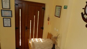 A dining area with a table set for four, wooden chairs, a vase with dried plants, and framed certificates on the wall. - Belegania (Oarja)