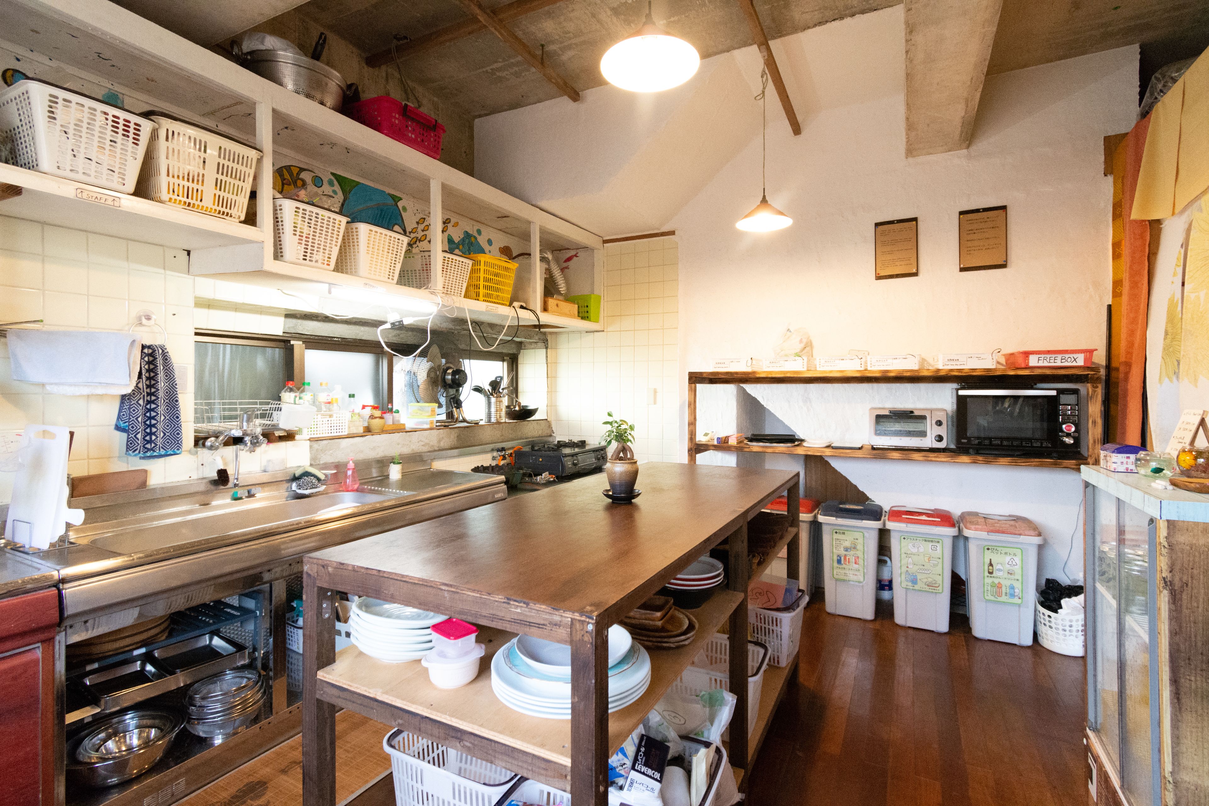 A kitchen with a wooden table, stainless steel appliances, and various kitchen items on shelves.