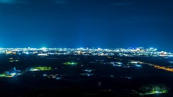 Une vue nocturne d’une ville, avec en arrière-plan une zone densément peuplée illuminée par de nombreuses lumières.