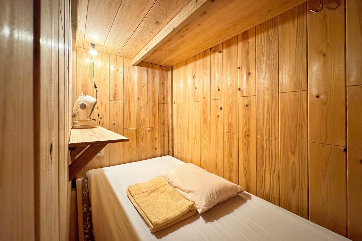 Une chambre dans un chalet en bois, avec un lit, une table de chevet et une lampe.