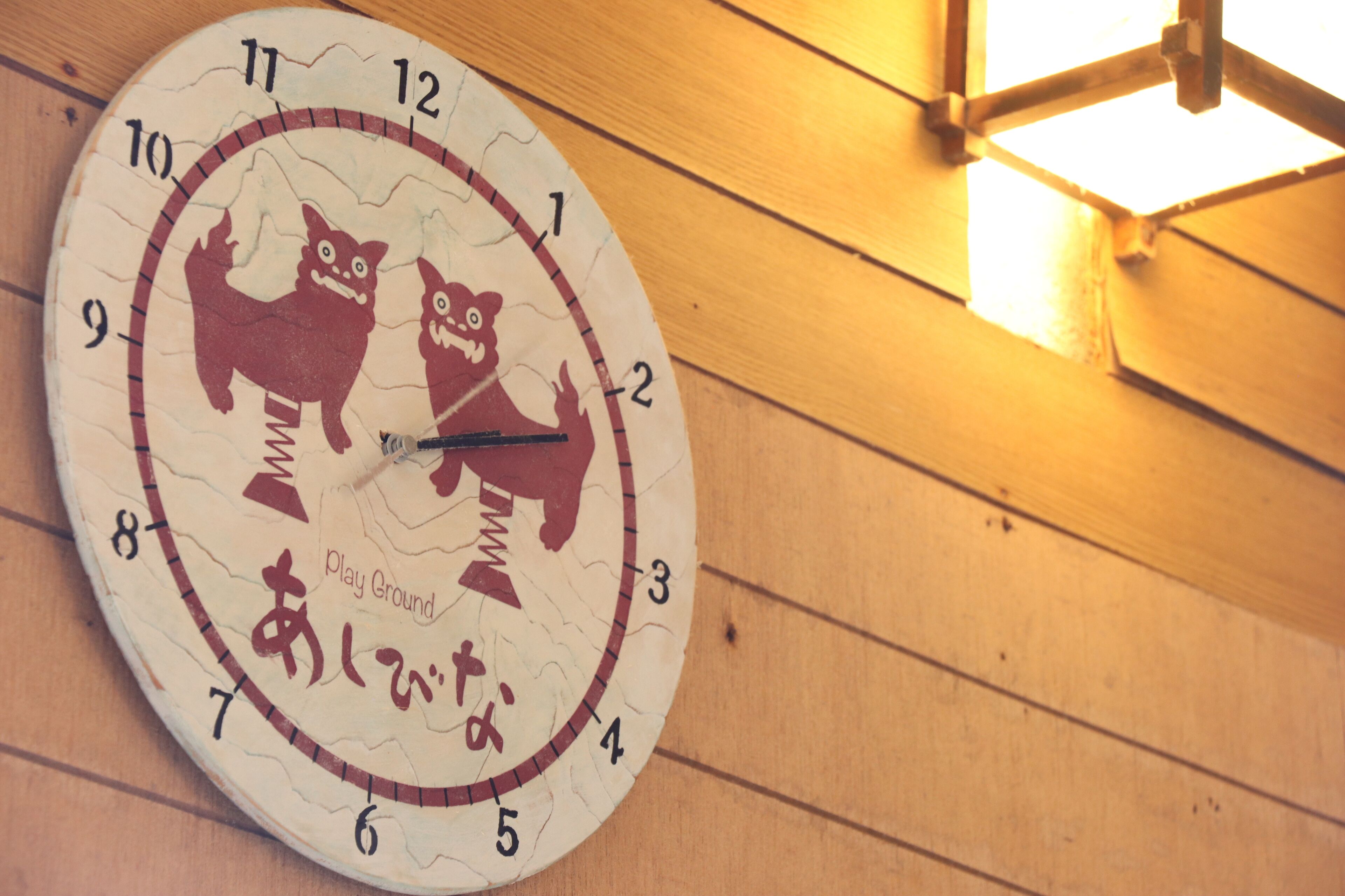 Un reloj de pared con diseño original que muestra dos gatos y caracteres japoneses.