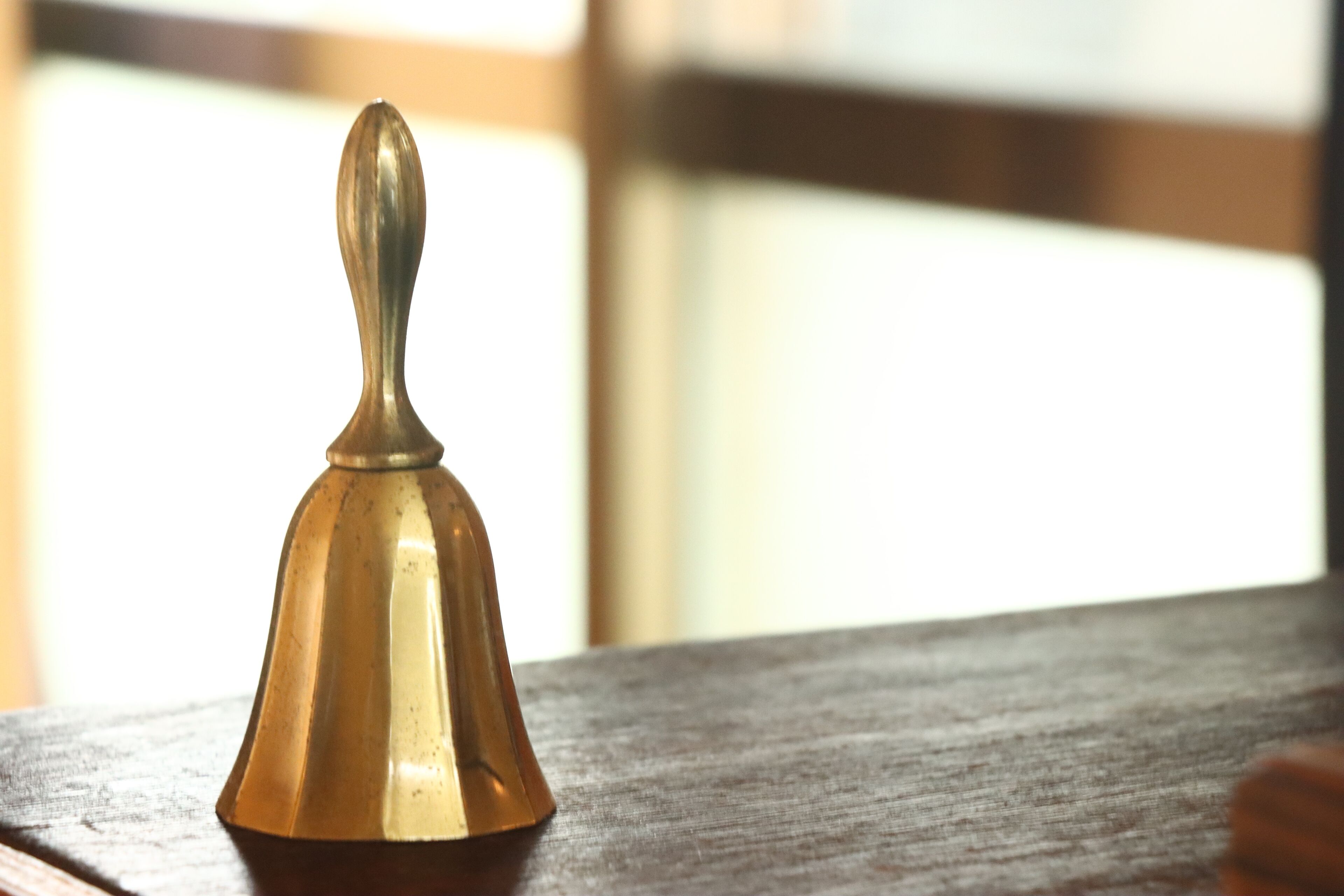 A brass bell on a wooden surface.