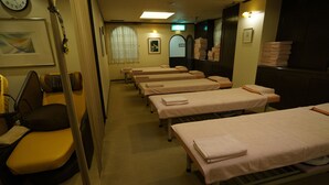 A room with multiple beds, a clock, and a mirror on the wall. - Executive Spa & Capsule WELLBE Fukuoka - Caters to Men (Fukuoka)