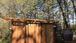 Una cabaña de madera con techo inclinado, una entrada pequeña y un panel solar en el techo.