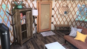 Un interior acogedor con un mueble de madera, un sofá, una mesita y una puerta.