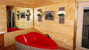 Eine Holzdiele mit einer roten Badewanne, Holzwänden und einem Spiegel, der den Raum widerspiegelt.