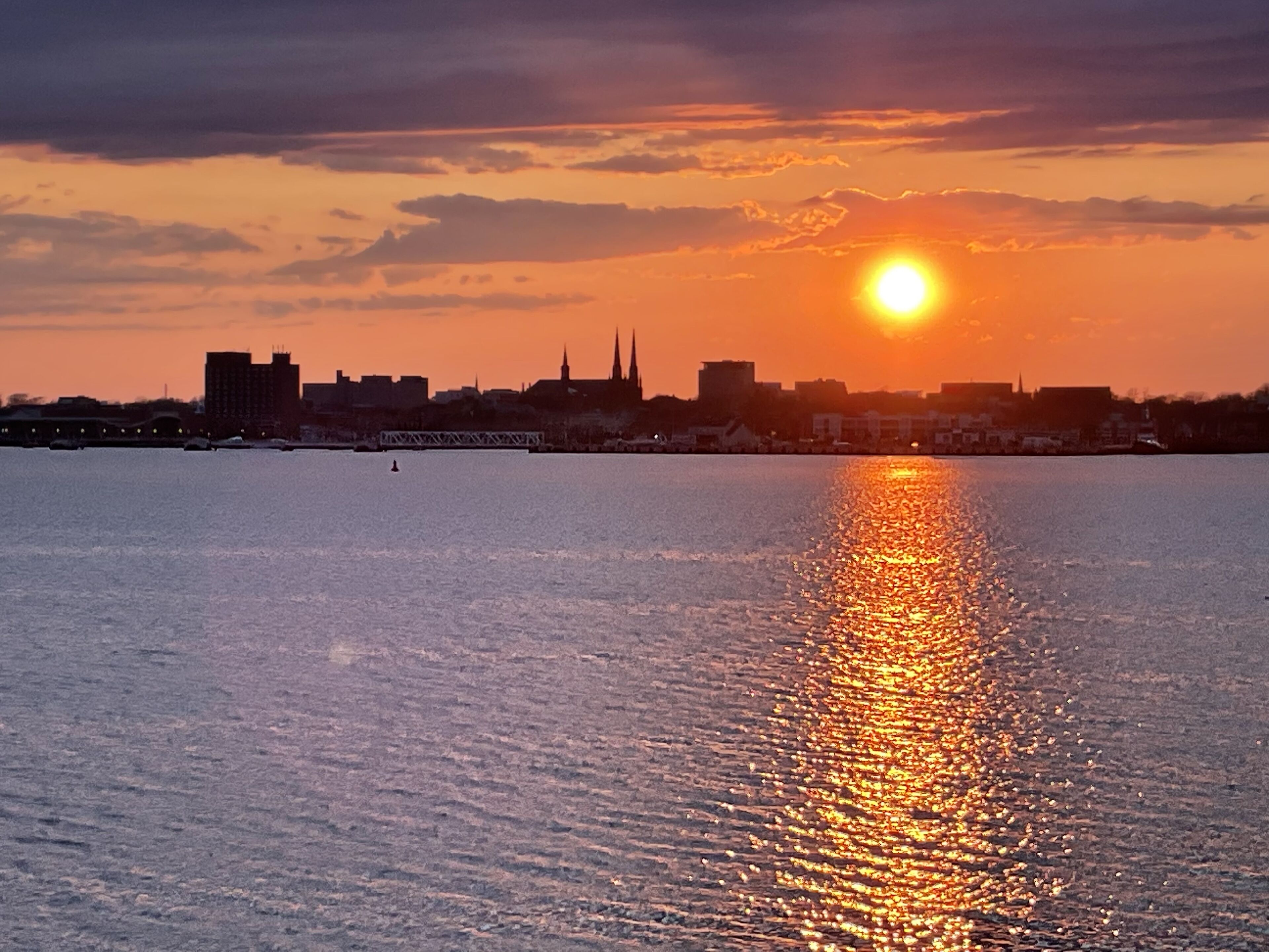A sunset over a body of water with a city skyline in the background.