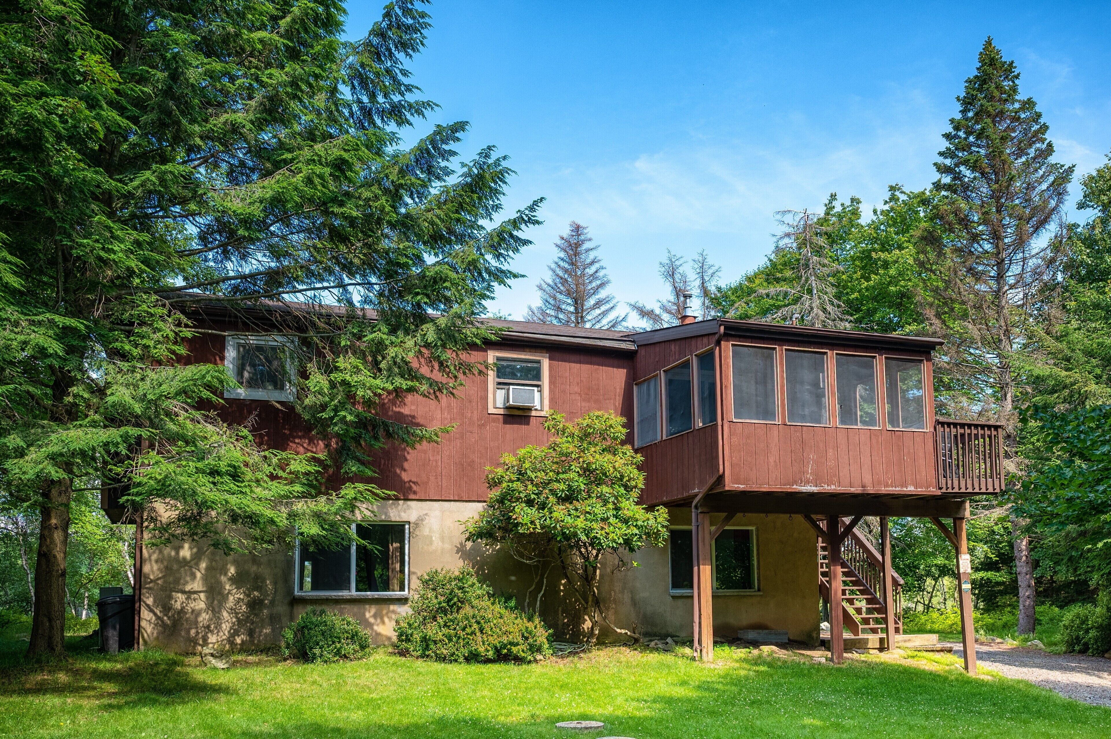 Ein zweistöckiges Haus mit einer Holzterrasse und einem Veranda.