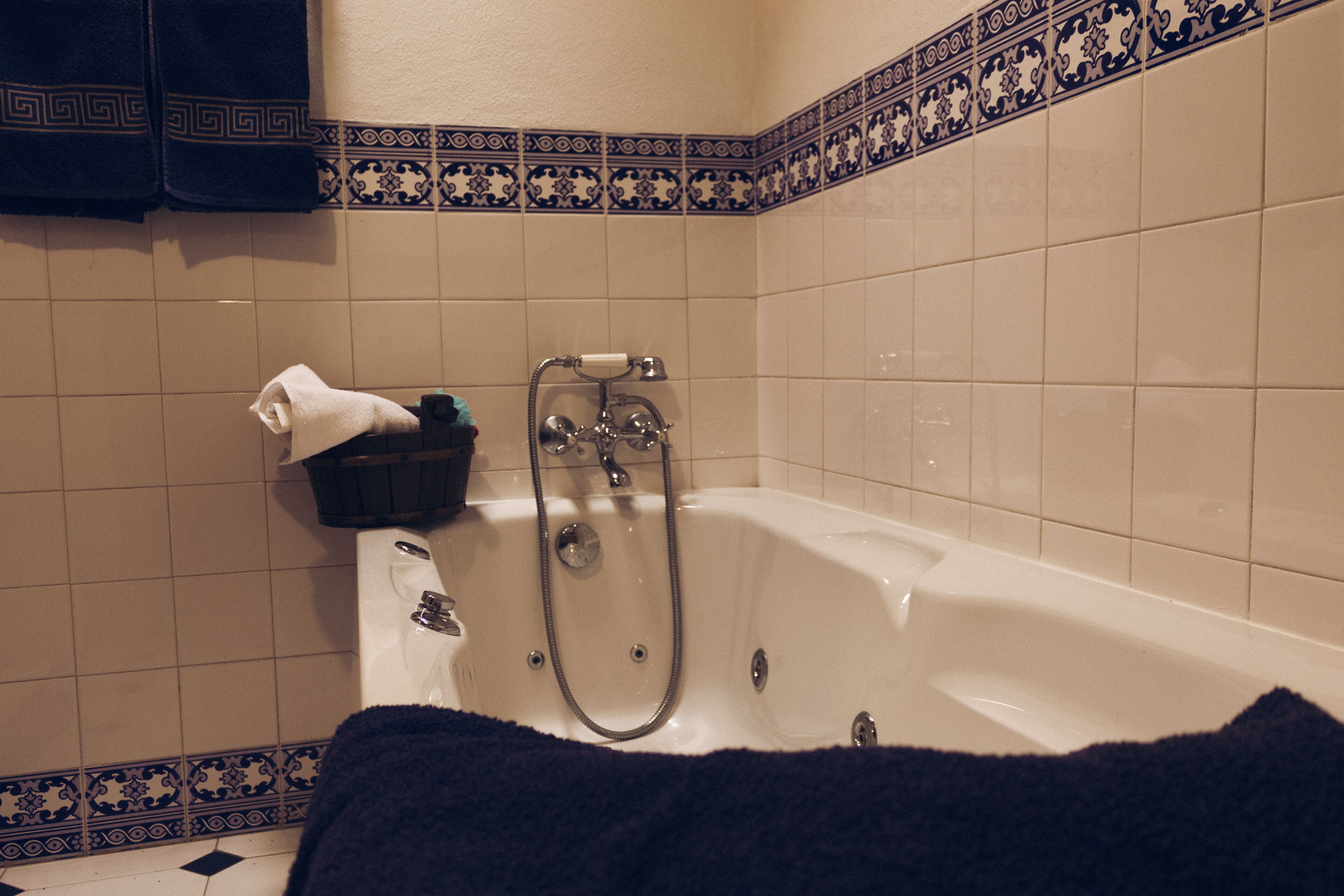 Ein Badezimmer mit einer Badewanne, einem Handtuch und einem schwarzen Korb.