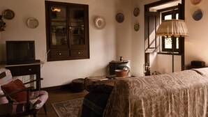 Ein traditionell eingerichtetes Zimmer mit Bett, Fernseher, Holzschrank und Fenster mit Blick.