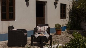 Eine Terrasse mit Korbmöbeln, einem Tisch mit Tee und einer Schüssel Essen sowie einem Blumentopf.