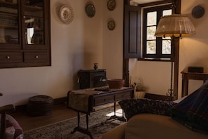 A cozy room with a sofa, a table with a bowl, a lamp, and a window with curtains. - Casa Rústica, for a perfect getaway  (Serra do Bouro)