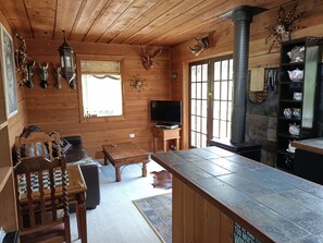 A wooden interior with a television, a fireplace, and various wall decorations. - The Huntsman Cabin (Warburton)