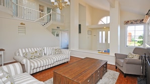 A spacious living room with a staircase, a wooden coffee table, and striped sofas. - Beggars Bridge Vineyard Homestead Pool Tennis (Rothbury)