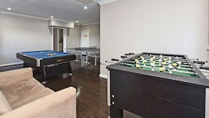 A room with a pool table, a foosball table, and a sofa. - Beggars Bridge Vineyard Homestead Pool Tennis (Rothbury)