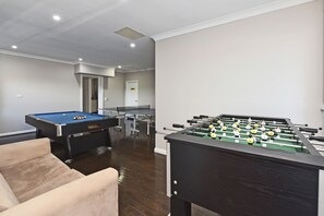 Una habitació amb taula de bitlles, taula de futbolí i un sofà.