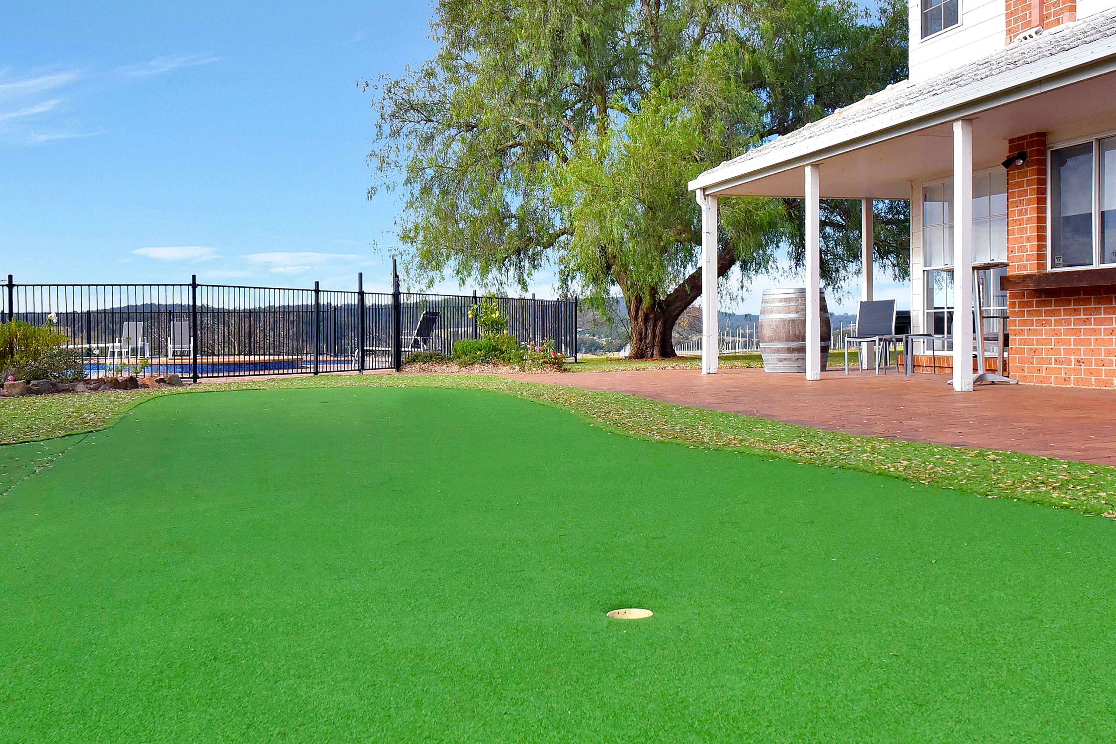 Ein Golfplatz mit grünem Kunstrasen, ein weißes Gebäude und ein Zaun im Hintergrund.