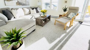 Ein Wohnzimmer mit einer Couch, einem Sessel, einem Couchtisch und einer Pflanze.