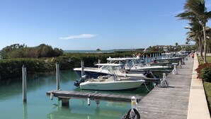 A marina with multiple boats docked along a wooden pier, surrounded by greenery and palm trees. - OCEANSIDE  ANGLERS REEF HOME- Gated community- Pool, Dock, Private Beach (Islamorada)