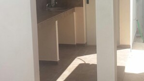 Un pasillo estrecho con una zona de cocina a la izquierda, que incluye un lavamanos y una encimera.